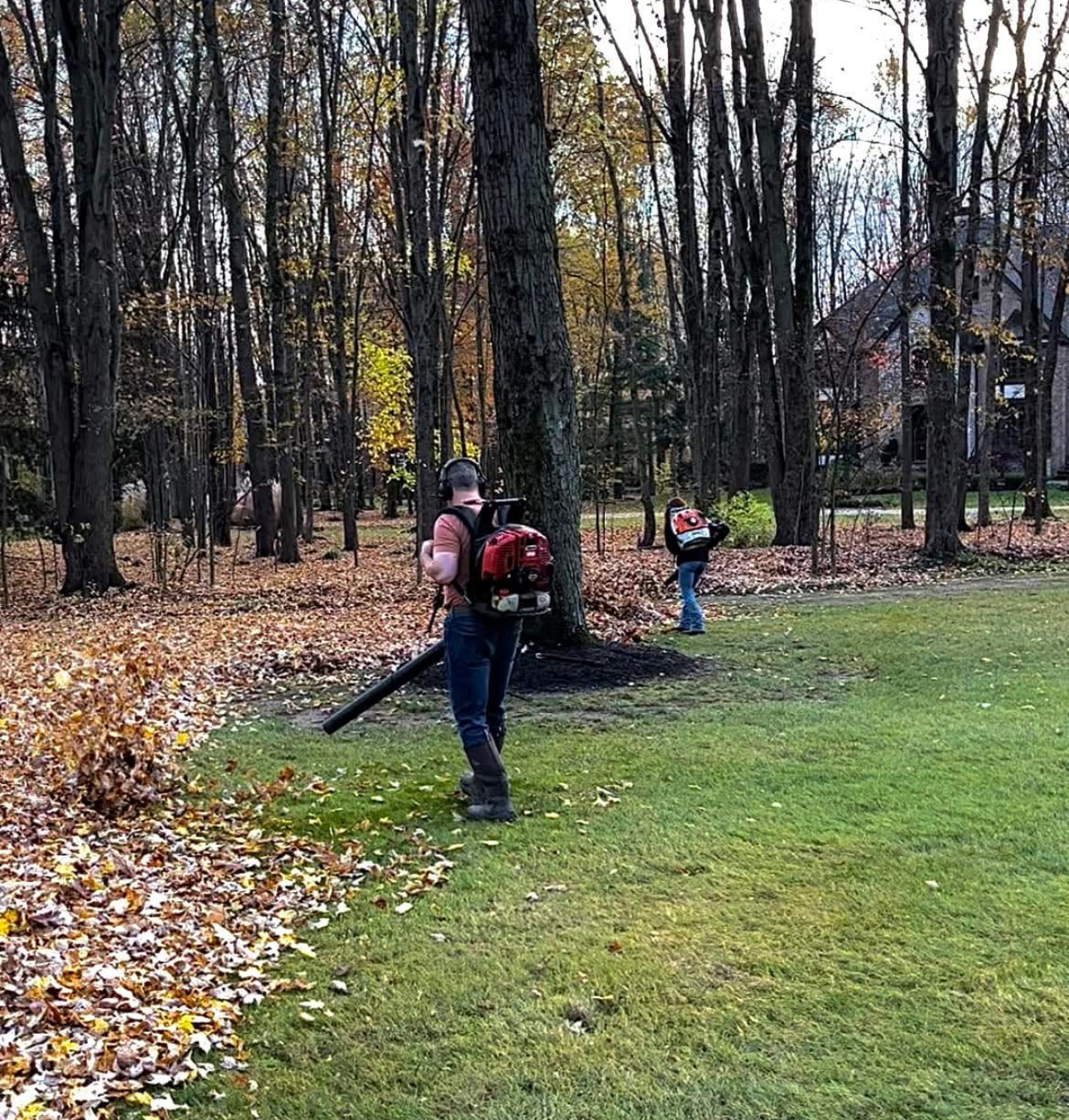 Eagle Scapes crew performing fall leaf cleanup with backpack blowers in a wooded Aurora yard