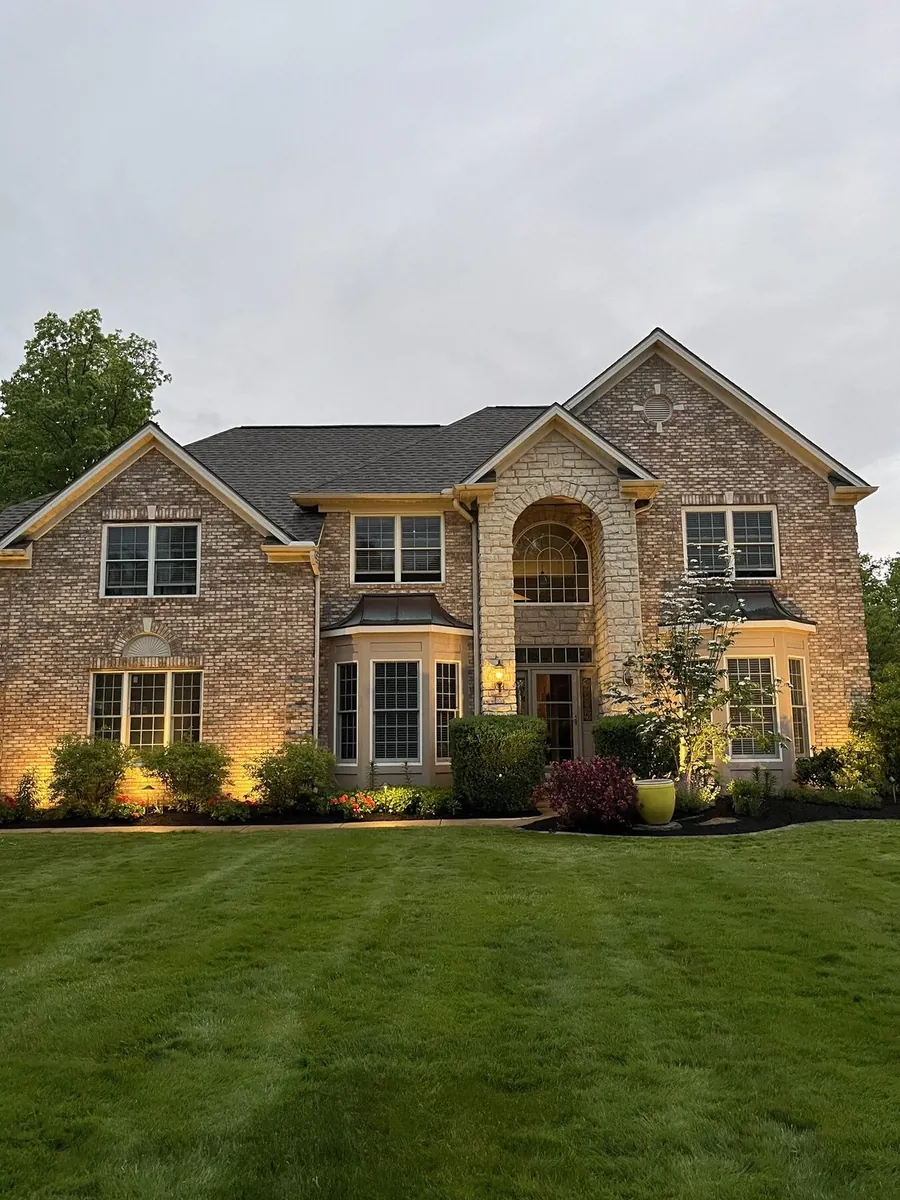 Twilight shot of mansion with mulched beds and architectural lighting