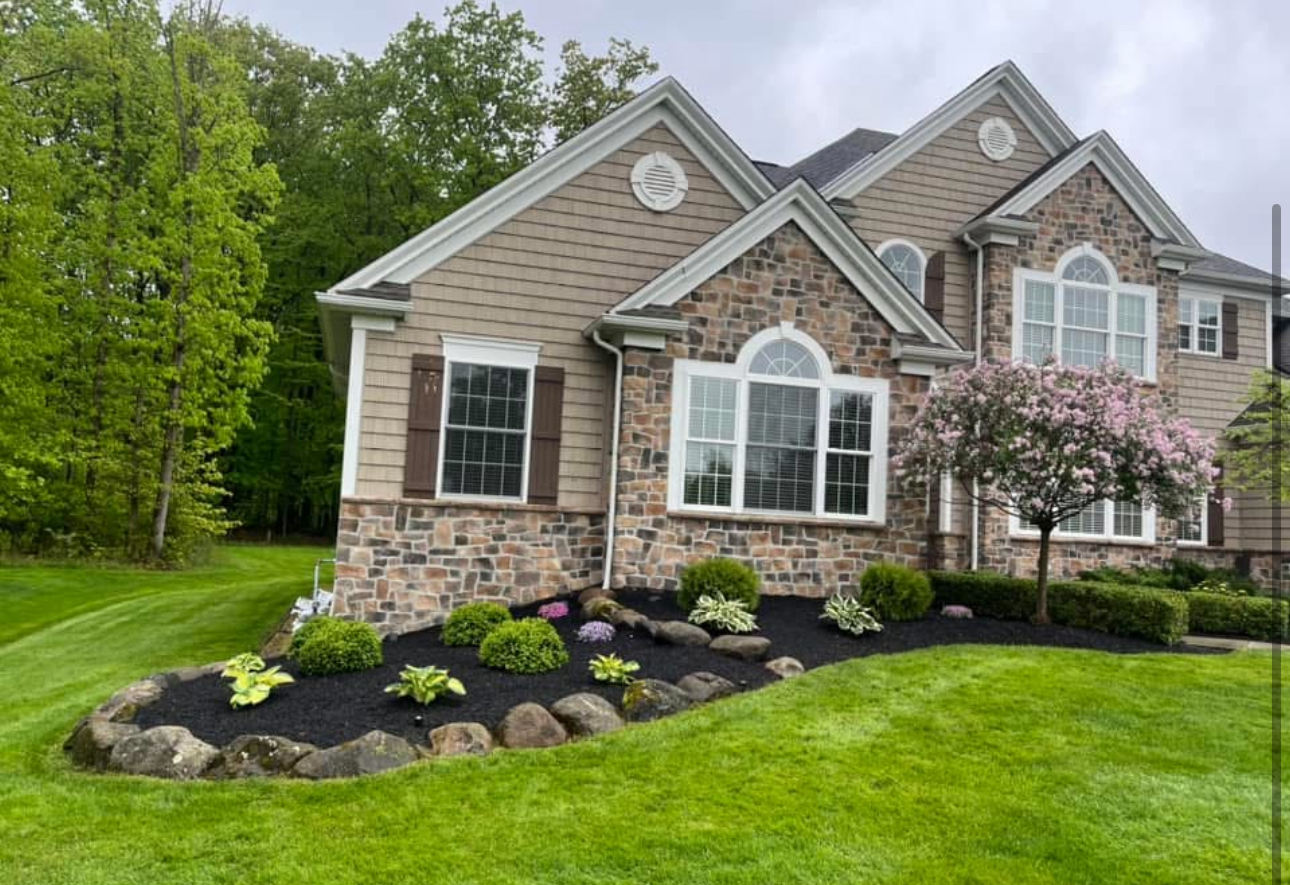 Stone and shingle home with fresh mulch beds and pavers in Chagrin Falls, Ohio