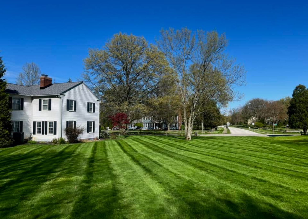White colonial home with crisp lawn stripes and blue sky in Aurora, Ohio