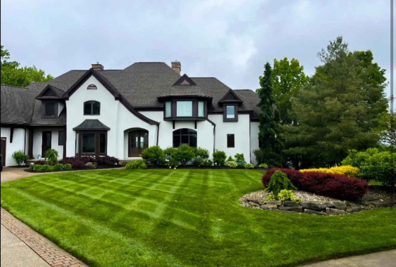 Freshly cut lawn with striped mowing pattern at a white stone-trimmed home in Aurora, Ohio